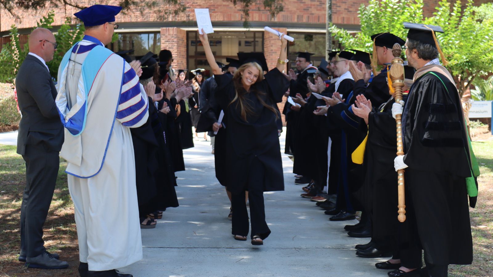 graduate walking through lines of faculty members at graduation